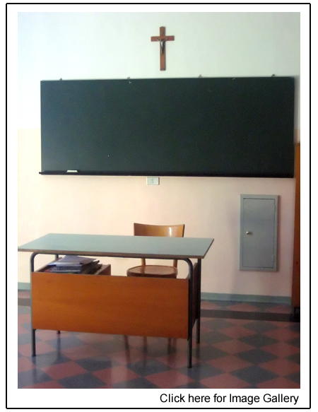 Classroom with empty desk and cross on wall