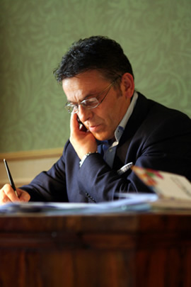 Patrizio Catena, Mayor of Cagli, as he speaks on his cell phone and writes with his fountain pen.
