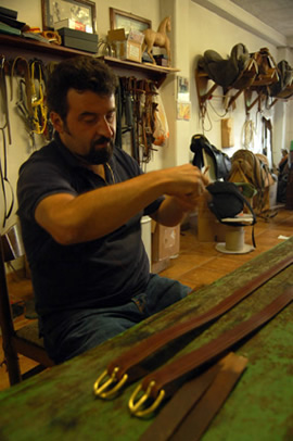 Maurizio Nicoletti hand-stitches the leather belts of his saddle's undercarriage.